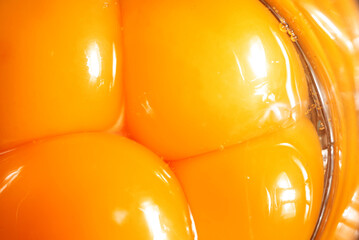 Close-up of egg yolks. Broken eggs and yolks next to each other. Smooth and moist surface with...