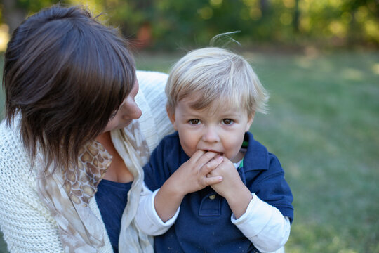 Pretty Mom Holding 2 Year Old Son In Lap Outdoors