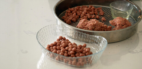 a woman rolling meatballs, a woman rolling tiny meatballs for meatballs,