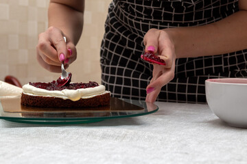 Equalizing the cherry filling of the cake with metal spoon. Selective focus. Picture for articles...