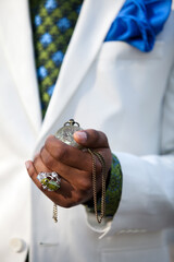 Close up of Male Fashion Model's hand holding pocket watch wearing a white suit