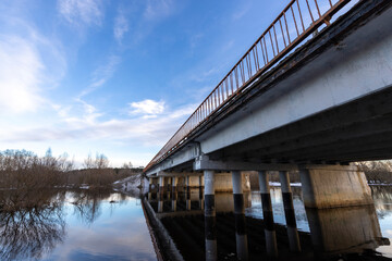 bridge over the river against the blue sky. March evening landscape.