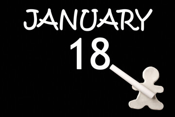 A small white plasticine man writing the date 18 January on a black board. Business concept. Education concept.