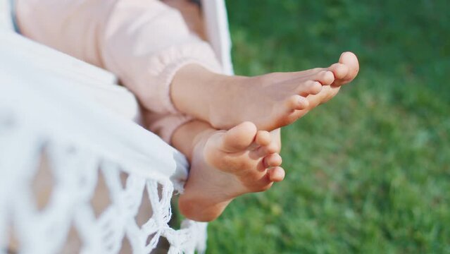 Young woman relaxes in the hammock in the garden with green grass