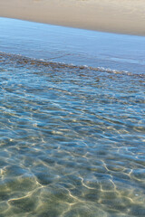 transparent sea water passing to a wide summer sandy beach