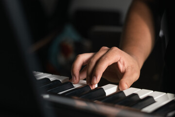 Fototapeta premium right hand detail of a young latin guy practicing on his piano or electric synthesizer. boy taking virtual lessons at home via internet. song and melody creations as a hobby.