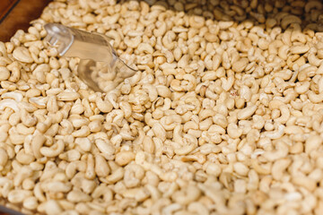 Shellless cashew nuts with shovel on counter in organic supermarket.