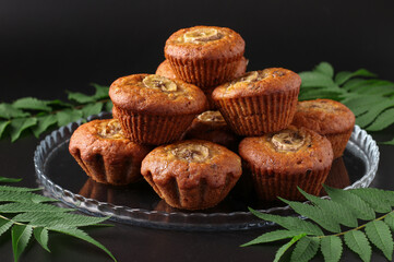 Homemade banana muffins with a slice of banana and cinnamon on a dark background