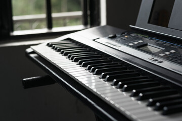 detail shot of a synthesizer next to a window on a cold day. piano ready for a virtual lesson of...