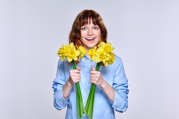 Portrait of young woman with bouquet of yellow flowers looking at camera