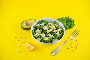 Kale avocado pine nuts cheese salad with lemon dressing in a bowl