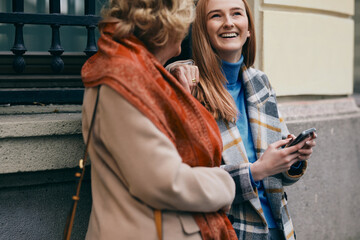 Obraz premium A grandmother and her grandchild standing on the street and reading messages on the phone.