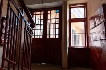 Photo inside the corridor of an old apartment building, the sun shines through the windows and front door