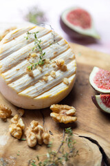 Camembert cheese with figs, walnuts and honey on a wooden board .