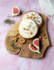 Camembert cheese with figs, walnuts and honey on a wooden board .