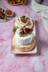 Camembert cheese with figs, walnuts, thyme and honey on a pink marble table .French dessert