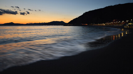 incredible colors and lights, a romantic sunset on the beach facing the sea in the magnificent Liguria