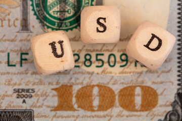 USD word written on wooden blocks on 100 dollar banknote background