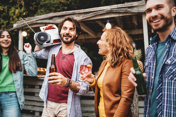 Obraz premium Cheerful friends talking and drinking beers and cocktails at beach party outdoor - Young millennials people having fun at weekend afternoon club - Youth lifestyle and summer concept .