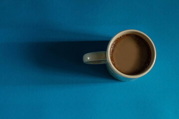 coffee in a white cup in the morning on a blue background