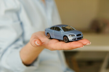 Car insurance. Woman holding toy car in hand.