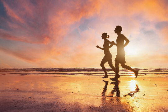 couple running, silhouettes of man and woman jogging at sunset beach