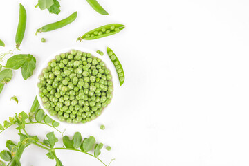 Fresh organic raw green peas in a bowl with peas pods and plants leaves on white background. Healthy eating, vegan and vegetarian legume food, raw food and detox super food, bean protein, top view