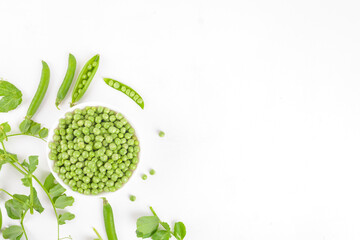 Fresh organic raw green peas in a bowl with peas pods and plants leaves on white background....