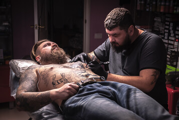 Tattooist makes tattoo pictures in tattoo studio