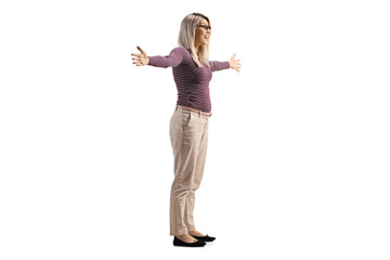 Full length profile shot of a young woman standing with arms wide open