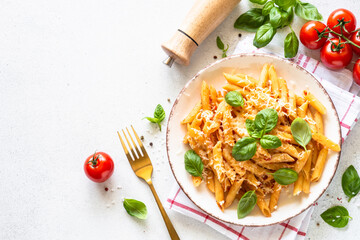 Pasta with tomato sauce, basil and parmesan on white table. Penne pasta with tomato sauce alla arrabbiata. Top view with copy space.