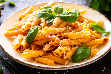 Traditional Italian pasta with tomato sauce, basil and parmesan cheese in white plate. Close up.