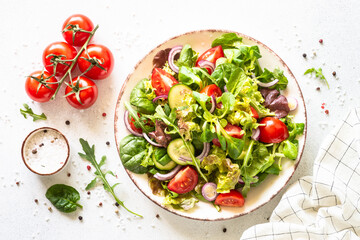 Green salad, veggie dish. Fresh salad leaves and vegetables in white plate. Healthy vegan food, diet food. Top view image.