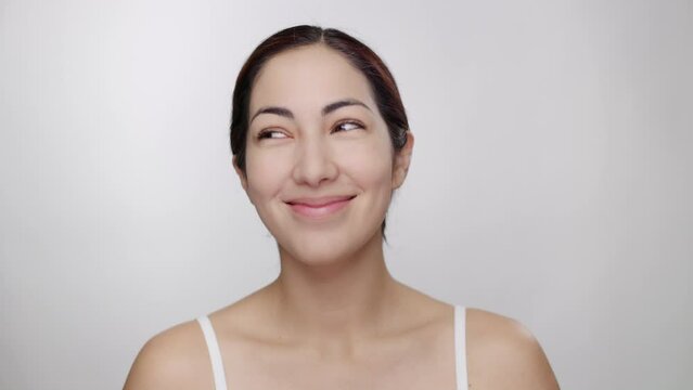 Beautiful female bruentte model on white background laughs playfully, looks down