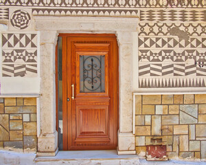 Pyrgi town, charateristic Sgraffito (Xistà) decorative pattern house wall and entrance with natural wood door, Chios island, Greece