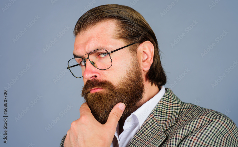 Wall mural Thoughtful bearded man in glasses. Pensive businessman in spectacles with hand on chin. Men fashion.