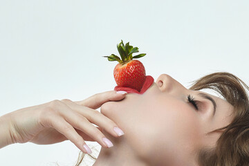 Obraz premium attractive girl holds strawberries in her lips. photo shoot in the studio