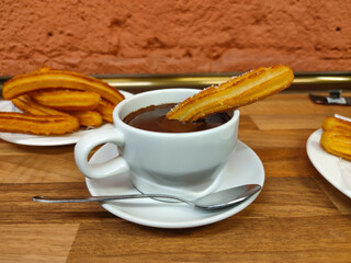 Traditional, typical spanish churros with hot chocolate sauce on a rustic wooden table
