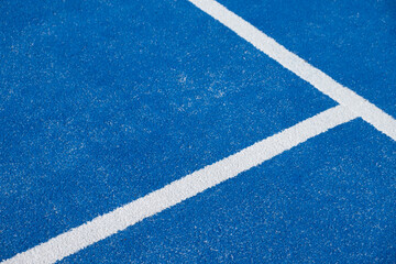 Fototapeta na wymiar white lines on a blue paddle tennis court with artificial grass. racket sports concept