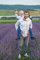 Young happy father having fun together and walking with little son in lavender field in summer