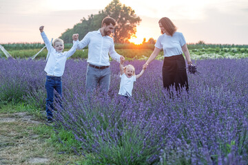 Happy family with two children are having fun outdoors in lavender field in summer. Sunset.