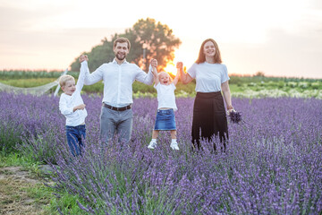 Happy family with two children are having fun outdoors in lavender field in summer. Sunset.