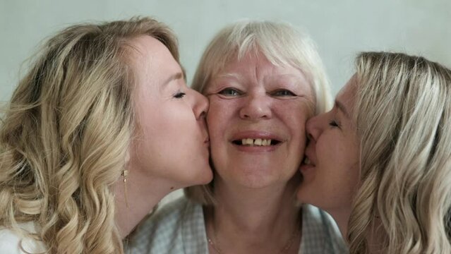 Happy family. An older mother with two twin daughters. Close-up of adult daughters kissing older mother on cheek. portrait of happy parents with adult children