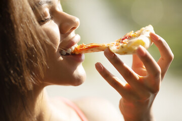 Black woman hand takes a slice of meat Pizza. Young woman eating pizza outdoor in street.