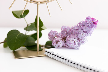 Flatlay composition with blank paper notepad, lilac flower, mirror on white wooden background. Flat lay, top view still life concept.