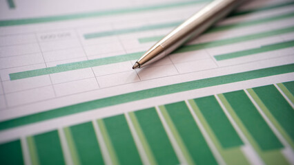 Closeup of analyzed graphs and charts with pen in office