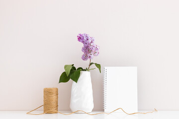 Clean notepad with spring lilac flowers on white wooden background