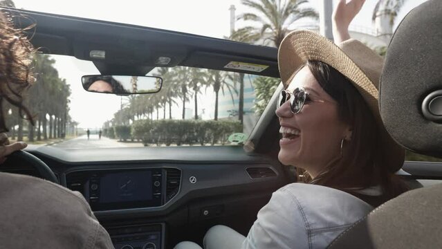 Happy young couple laughing together while driving a convertible car on holidays - Two millennial people having fun during road trip on summer vacation - Travel and rental auto service concept