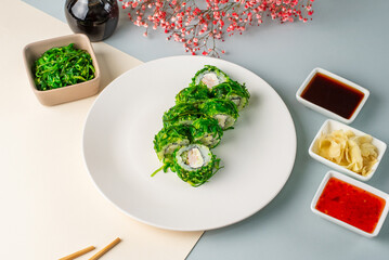 japanese sushi rolls with shrimp and chuka salad on a colored ba
