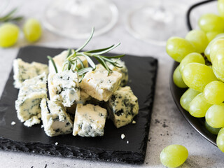 Sliced ​​blue cheese on a black stone tray.